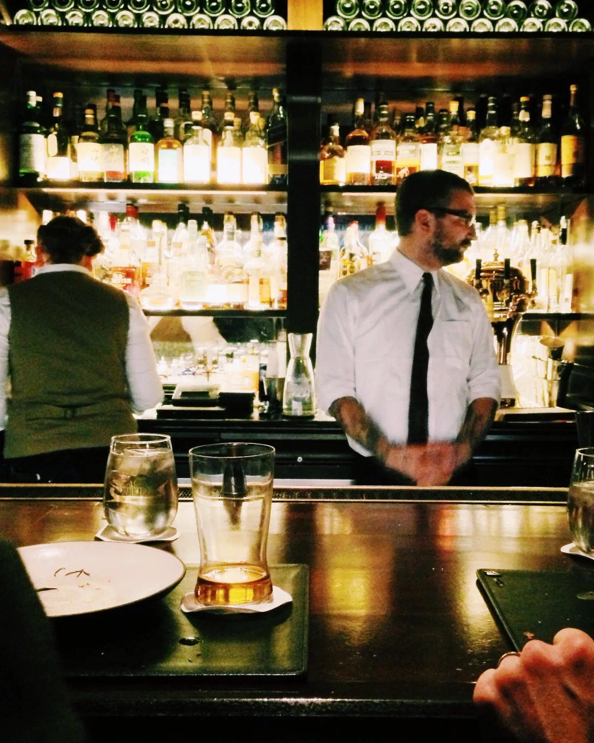 A bartender pouring a cocktail at a dimly lit bar
